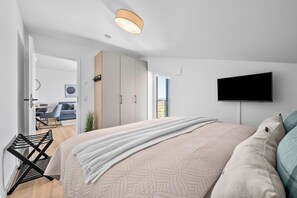Een moderne slaapkamer met een bed, een televisie en uitzicht op de omgeving.