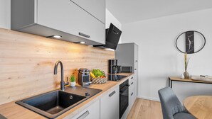 Eine moderne Küche mit Holzrückwand, Edelstahlgeräten und einem eingebauten Backofen.