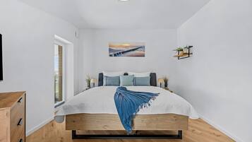 Una camera da letto moderna con un letto, un quadro, una mensola con piante e una finestra.
