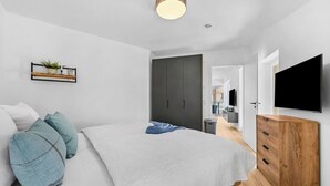 Un dormitorio moderno con cama, televisor y armario.