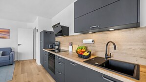 Una cocina moderna con encimera negra, un lavamanos y un protector de pared de madera.