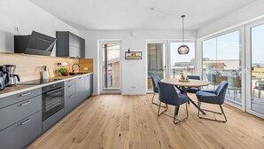 Una cocina moderna con gabinetes grises, una encimera de madera y un comedor con una mesa redonda y sillas azules.