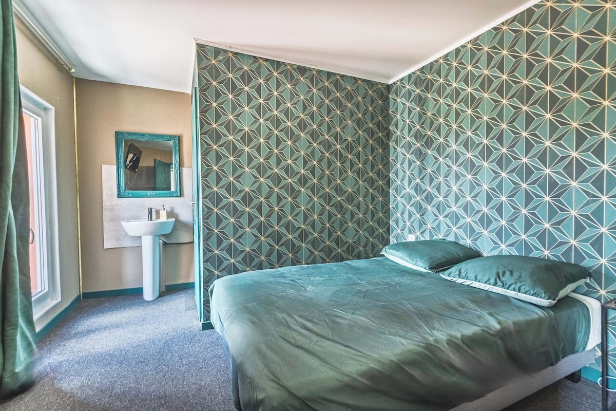 Ein Zimmer mit einem Bett, einem Waschbecken und einem Spiegel.