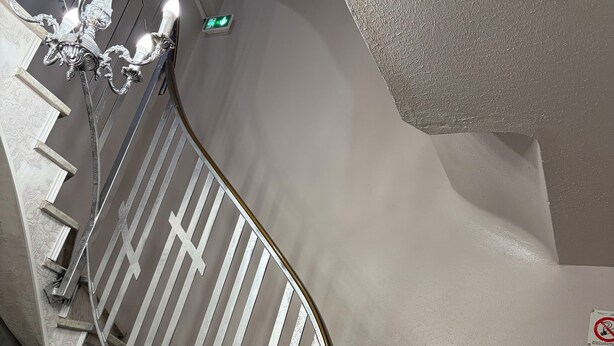 Eine Treppe mit weißer Geländer, einem Chandelier und einem Rauchmelder an der Wand.