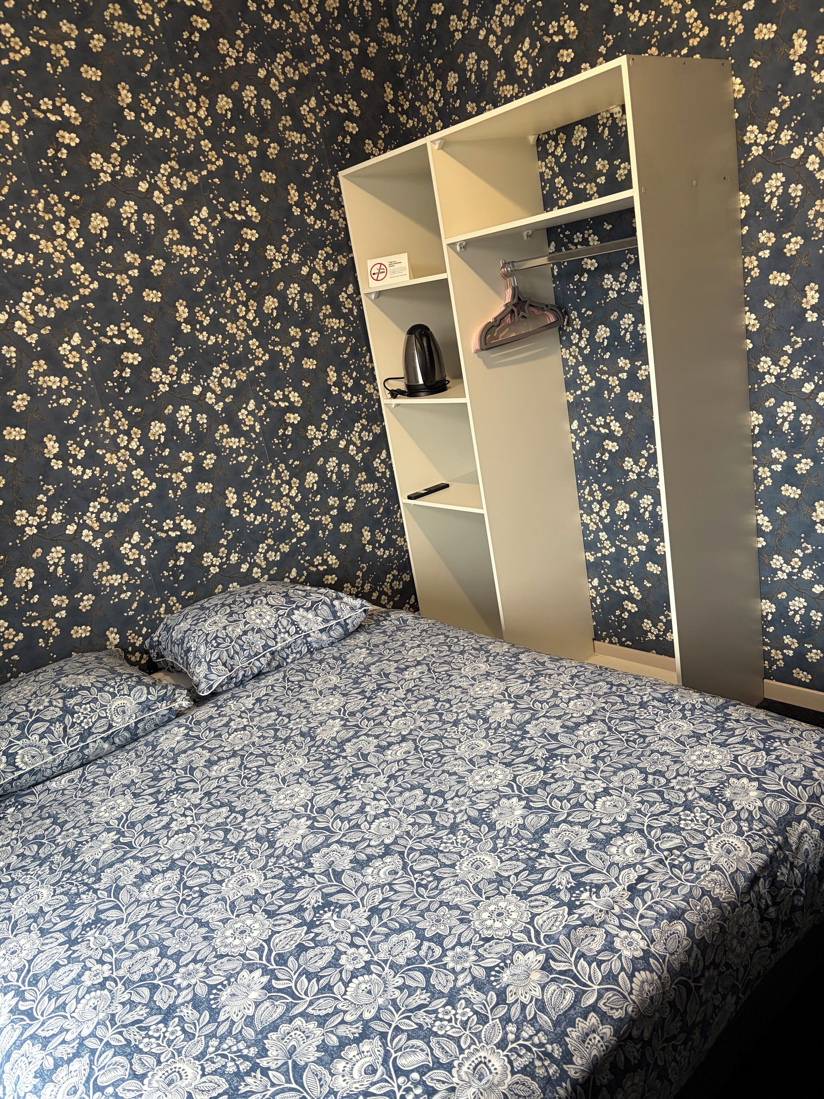 Un dormitorio con una cama, un armario y una mesita de noche.