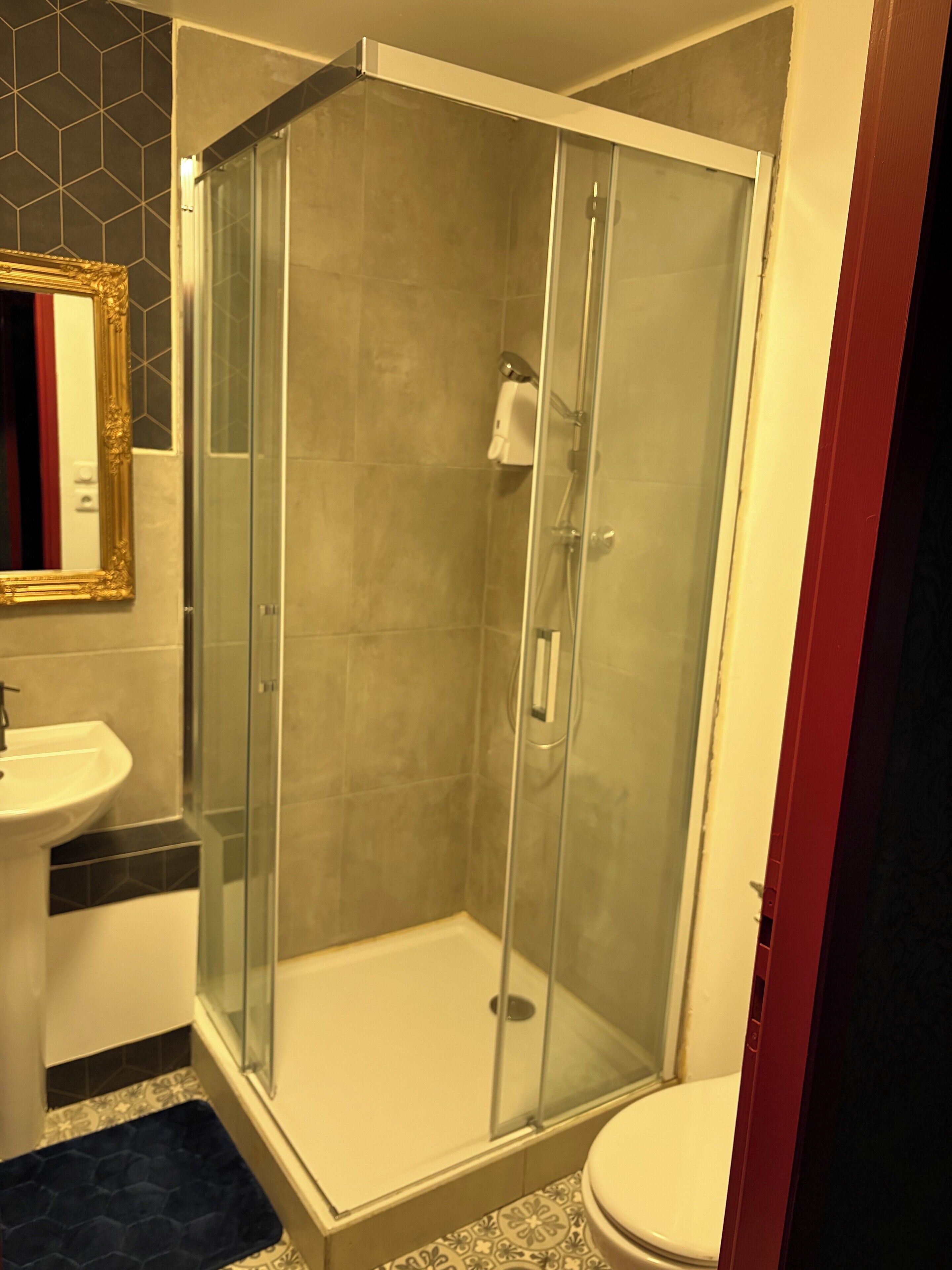 A bathroom with a glass-enclosed shower, a sink, and a toilet.