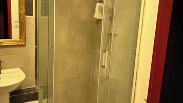 A bathroom with a glass-enclosed shower, a sink, and a toilet.