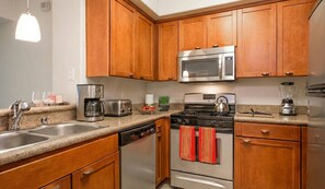 A modern kitchen with wooden cabinets, stainless steel appliances, a dishwasher, and a stove with red towels. - 1 BA Marina Del Rey - Quick Trip To Venice Beach (Marina del Rey)