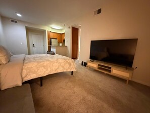 A bedroom with a bed, a TV, and a kitchenette in the background. - 1 Bedroom In Central Marina Del Rey - Close To Beach (Marina del Rey)