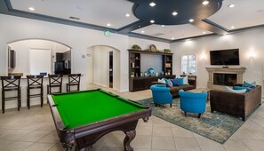 A pool table, blue armchairs, a brown sofa, a fireplace, and a television in a well-lit room with tiled flooring and white walls. - 1 Bedroom In Central Marina Del Rey - Close To Beach (Marina del Rey)