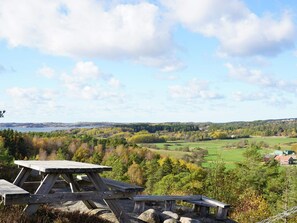A picnic table set on a rocky outcrop overlooking a scenic landscape with a lake and rolling hills. - 4 Star Holiday Home in Fjallbacka (Fjallbacka)