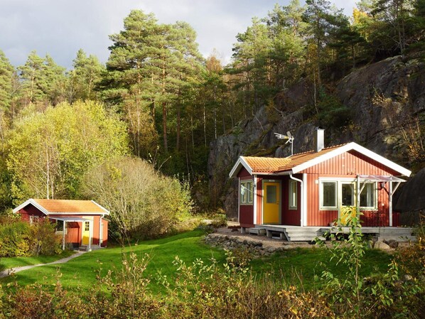 A red cabin with a yellow door, a smaller red cabin, and a rocky hillside in the background. - 4 Star Holiday Home in Fjallbacka (Fjallbacka)