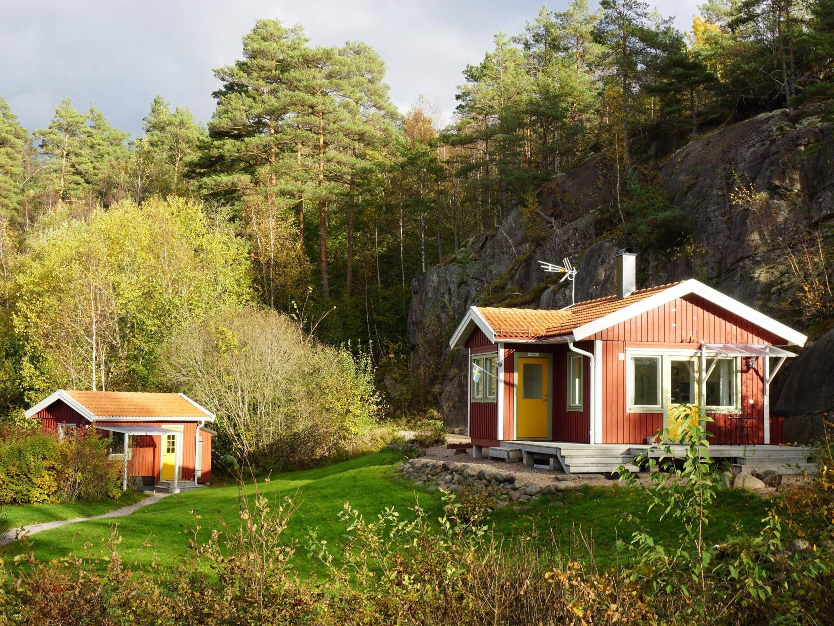A red cabin with a yellow door, a small porch, and a chimney.