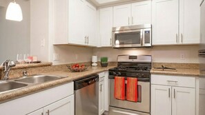 A modern kitchen with white cabinets, stainless steel appliances, a granite countertop, and a dish rack. - Cozy 1-bedroom apartment in delightful Marina del Rey with AC (Marina del Rey)
