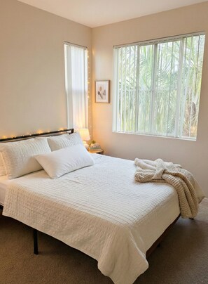 A bedroom with a bed, a nightstand, a lamp, a picture on the wall, and a window with blinds. - Cozy 1-bedroom apartment in delightful Marina del Rey with AC (Marina del Rey)
