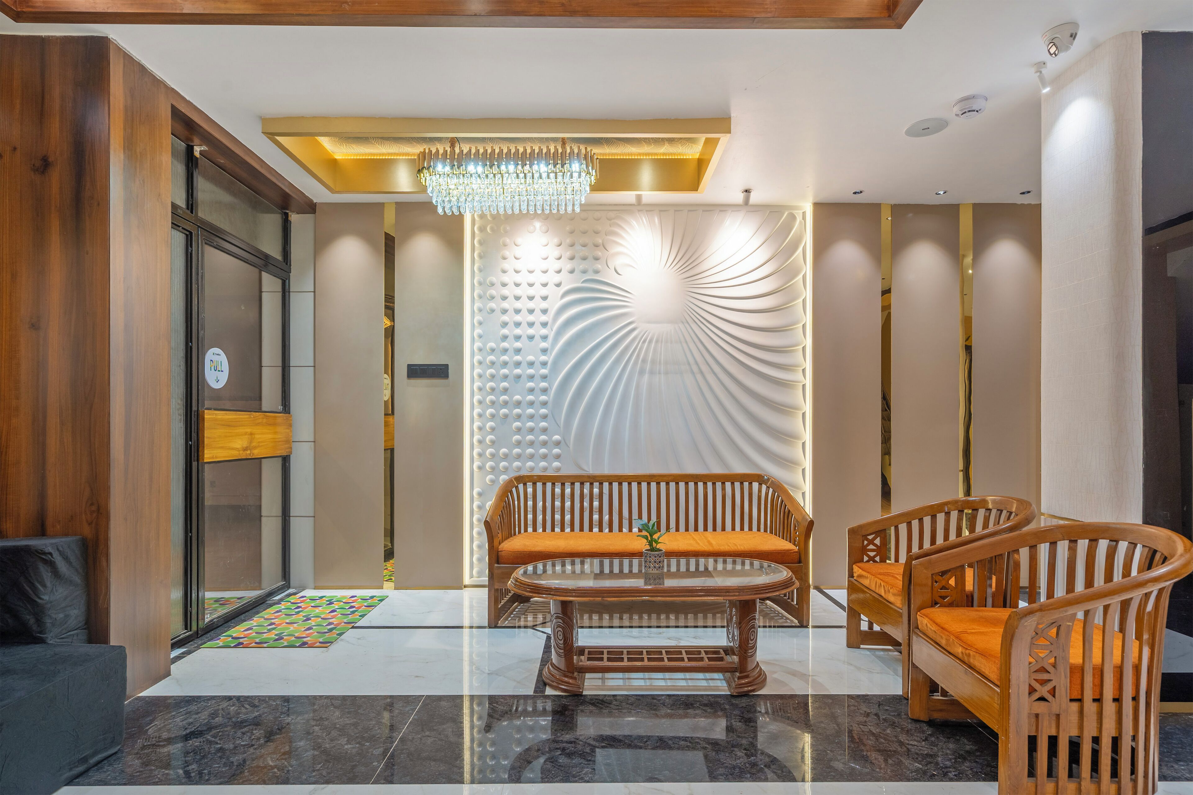 A modern lobby with a wooden bench, a glass coffee table, and a decorative wall.