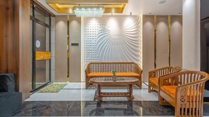 A modern lobby with a wooden bench, a glass coffee table, and a decorative wall. - Treebo Grace Stays (Bhubaneshwar)