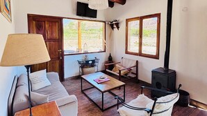 A cozy living room with wooden flooring, a sofa, a coffee table, and a fireplace. - La Nochera Killa Cabins (Tilcara)