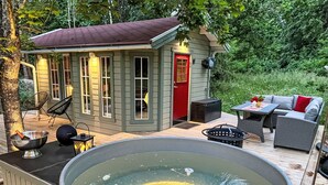 Een hottub op een houten terras, met een gebouwtje op de achtergrond.