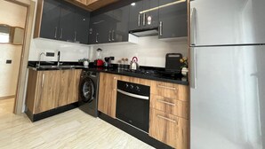 Una cocina moderna con armarios de madera, un refrigerador de acero inoxidable, un horno empotrado y una lavadora.