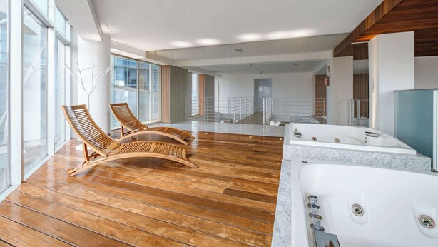 Un espacio interior amplio con piso de madera, un ventanal grande y una bañera de hidromasaje.