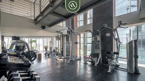 Un gimnasio moderno con diversos equipos de ejercicio, ventanas amplias y suelo pulido.