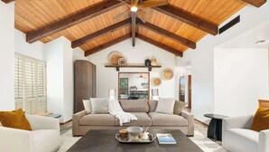 A living room with a high ceiling, wooden beams, a beige sofa, white armchairs, and a coffee table with decorative items. - NEW 2M Luxe N Scottsdale Estate w Heated Pool (Scottsdale)