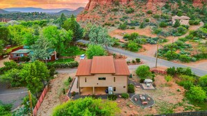 A house with a red roof, surrounded by greenery and a rocky mountain backdrop. - NEW Cimaron Butte View Terrace 2 Kings Firepit (Sedona)