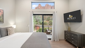 Una camera da letto con un letto grande, una TV a muro e vista sull'esterno tramite una porta scorrevole.
