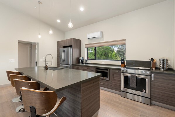 Una cocina moderna con una isla central, electrodomésticos de acero inoxidable y vistas al exterior.