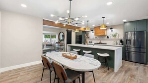 A modern kitchen with a central island, bar stools, and a stainless steel refrigerator. - NEW The Palmera Updated 4BR Retreat w Pool (Scottsdale)