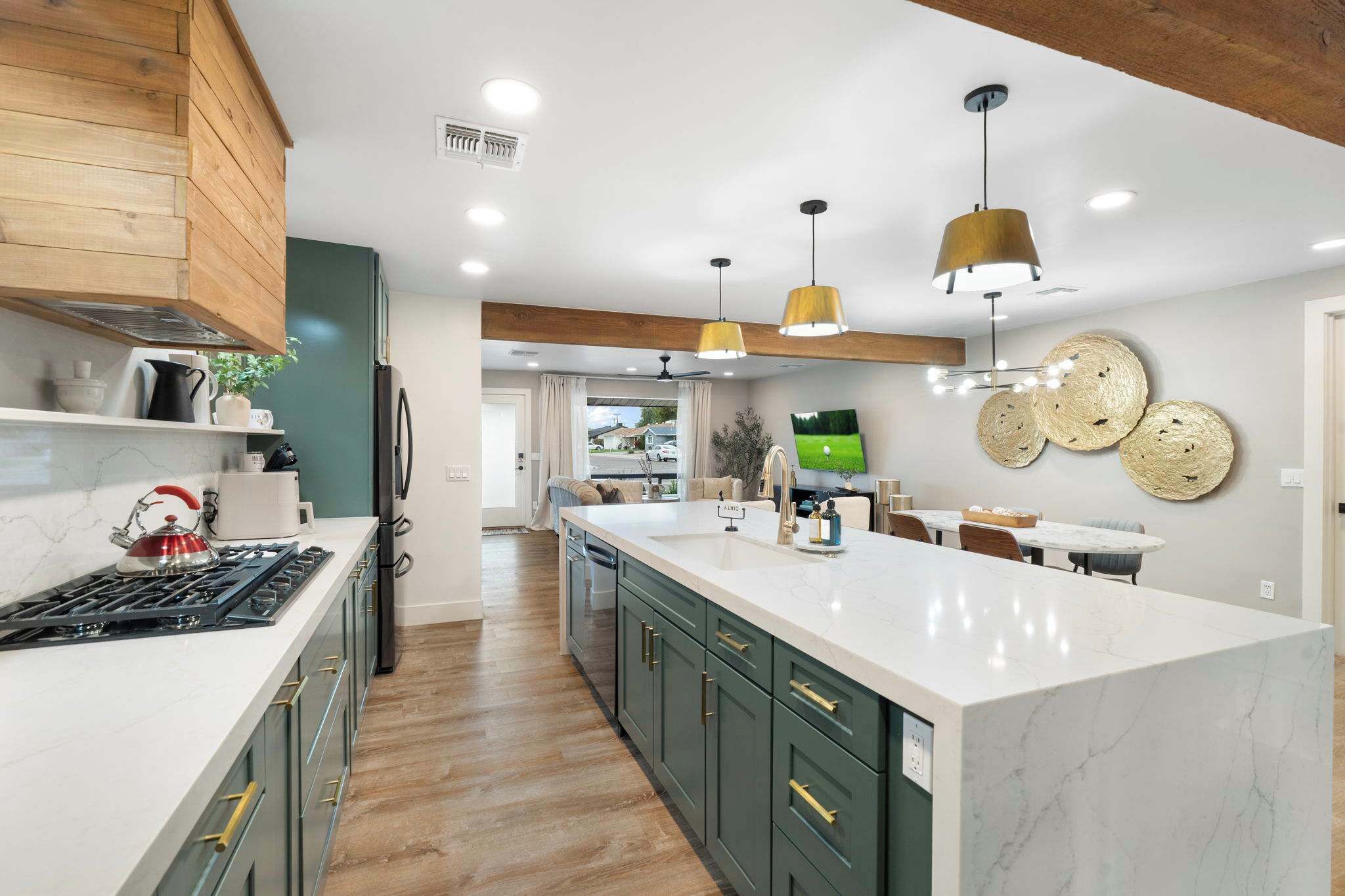 A modern kitchen with a central island, wooden ceiling beams, and pendant lighting.