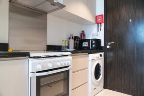 Eine kompakte Küche mit Herd, Backofen, Mikrowelle und Waschmaschine.
