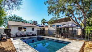 Une maison moderne dotée d’une piscine, d’un jardin clôturé et d’un patio couvert.