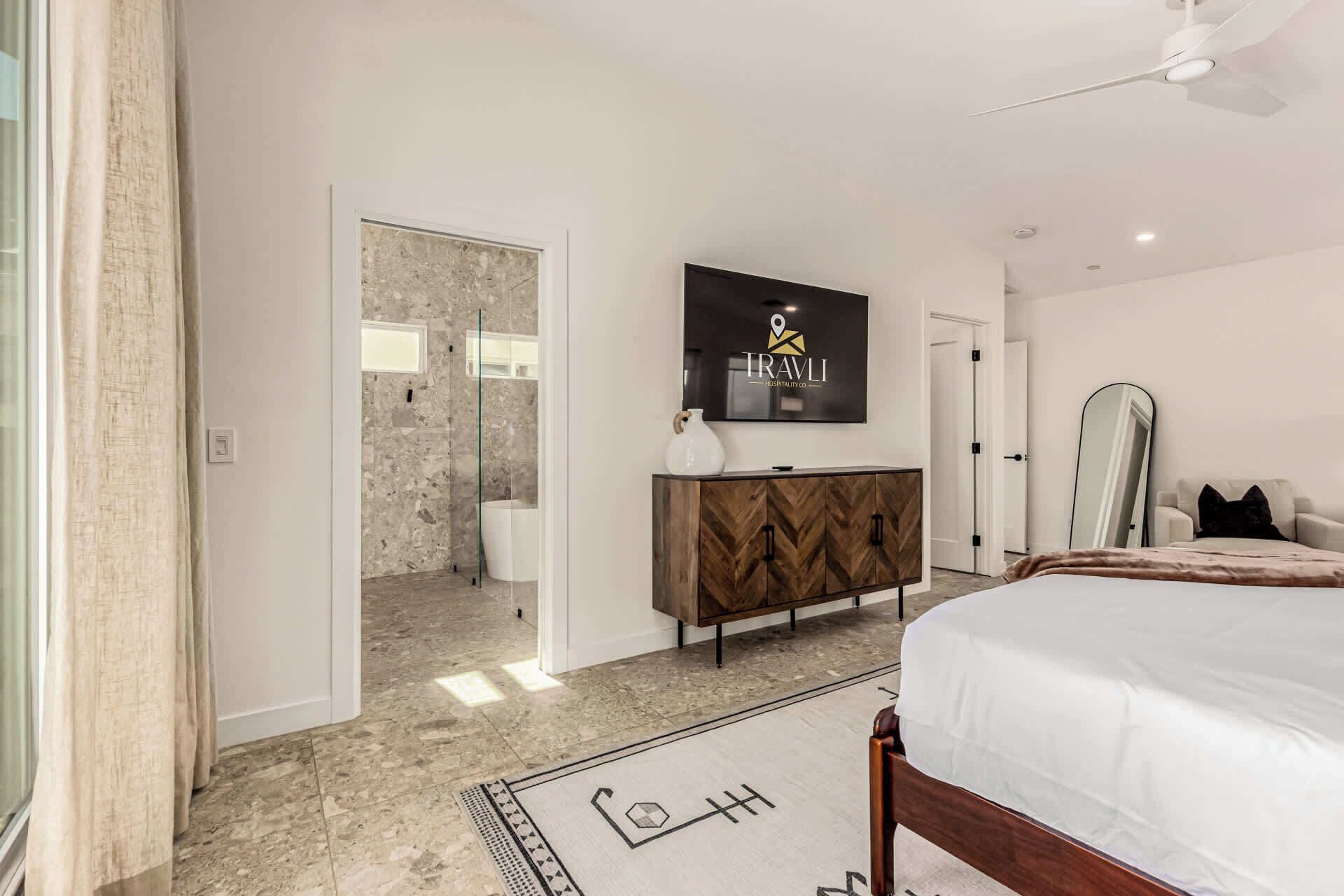 A bedroom with a bed, a dresser, a mirror, and a shower area.