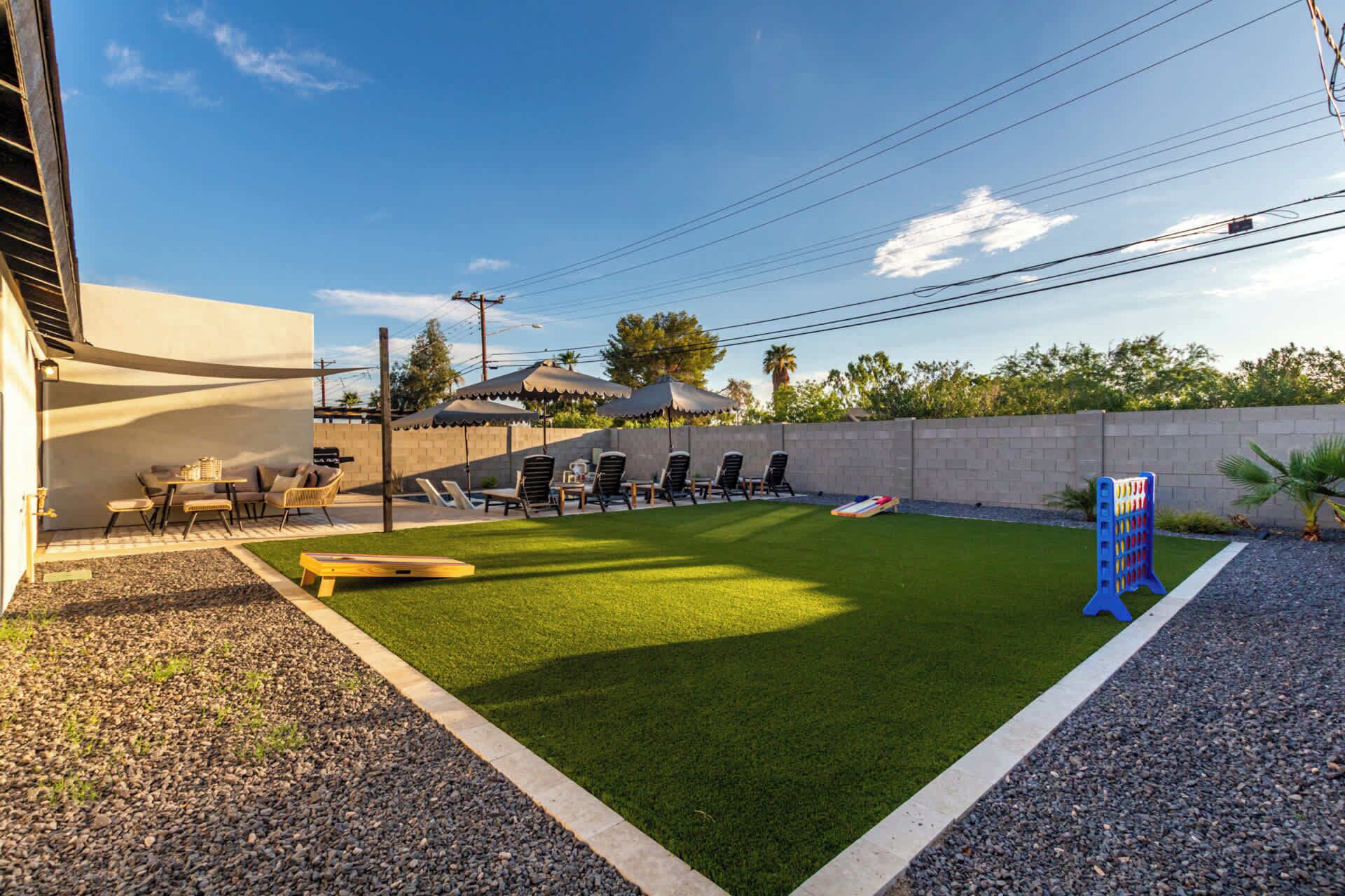Un jardin avec une pelouse artificielle, une table de billard, un coin salon extérieur et un espace de jeux pour enfants.