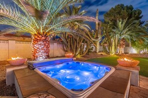 A hot tub surrounded by palm trees and cacti, with a fire feature nearby. - NEW Grotto Falls Retreat Pool w Slide Spa Putt Grn (Scottsdale)