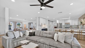 A modern living room with a sectional sofa, a dining area, and a kitchen with white cabinets and a bar. - NEW Casa Bravada Heated Pool Spa Pickleball (Scottsdale)