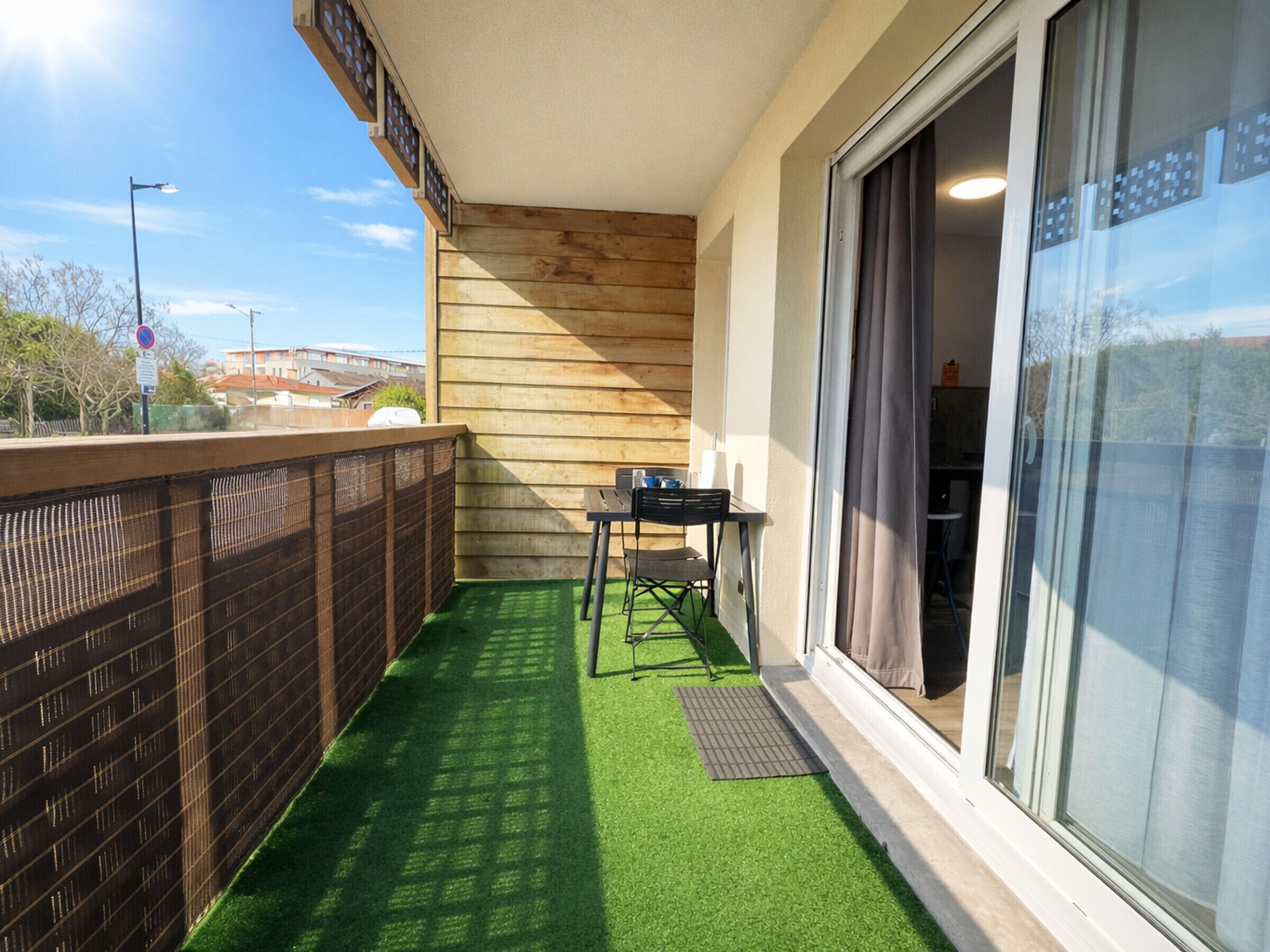 A balcony with artificial grass, a table, and chairs.