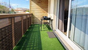 En balkon med kunstgræs, et bord og stole.
