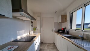 Cocina compacta con encimera de madera, un lavamanos y un ventanal que proporciona luz natural.