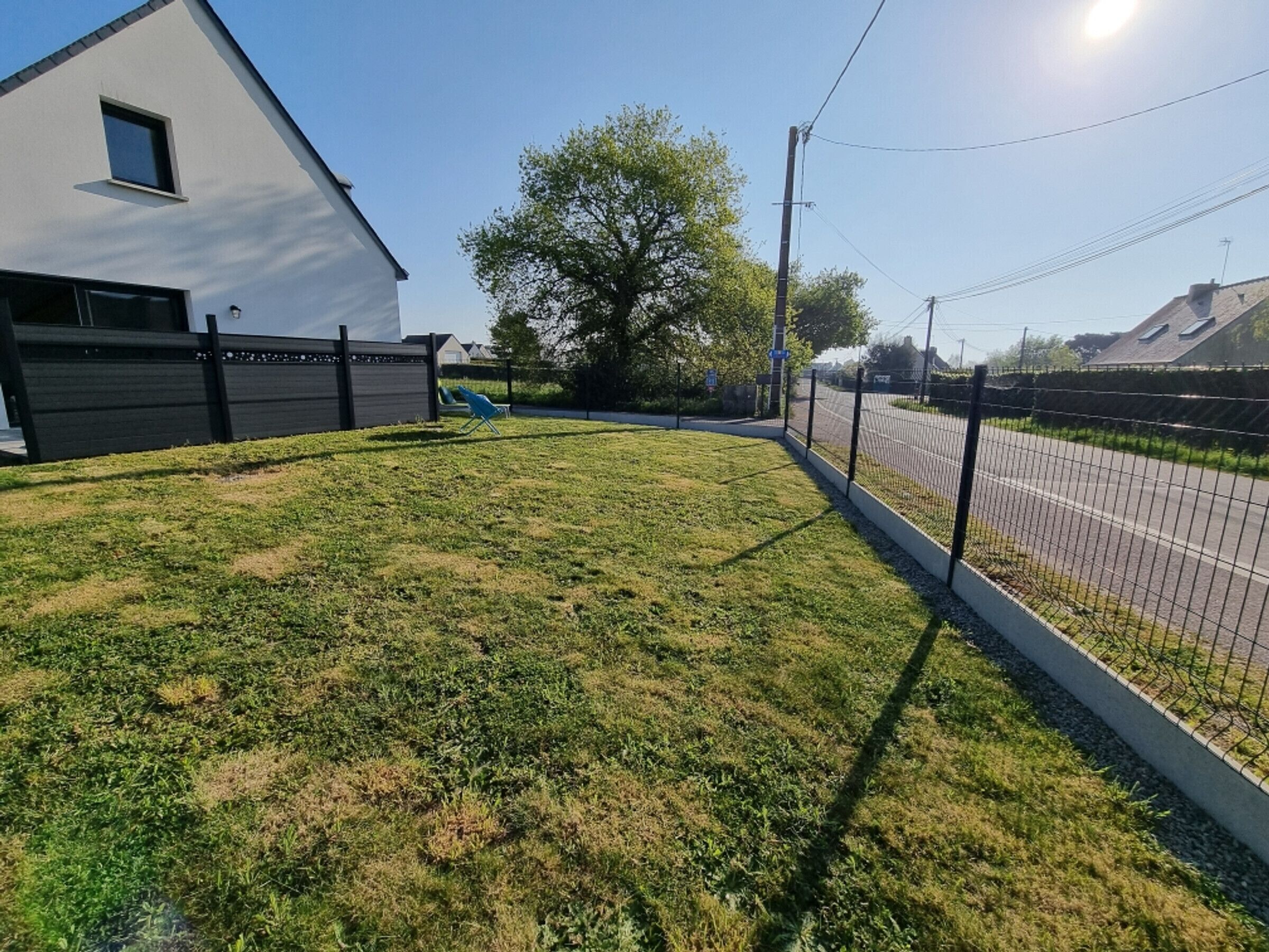 A residential area with a house, a fenced yard, and a road.