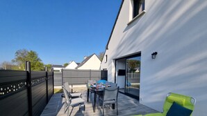 Un patio exterior moderno con una mesa de comedor, sillas y una butaca amarilla.