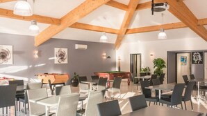 A spacious indoor area with high ceilings and exposed wooden beams, featuring multiple tables and chairs arranged for dining or meetings. - Mobile home for 6 ppl with terrace (Saint-Maurice-d'Ibie)