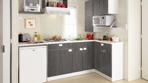 A compact kitchen with dark grey cabinets, a white countertop, a microwave, a toaster, and a small refrigerator. - Mobile home for 6 ppl with terrace (Saint-Maurice-d'Ibie)
