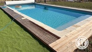 Et rektangulært pool med en træterrasse hele vejen rundt.