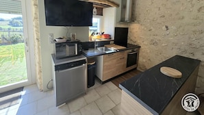 Et moderne køkken med indbygget mikroovn, en brødrister og en vask. Der er en træbordplade og en backsplash i sort marmor.
