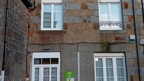 Un edificio con dos ventanas, una puerta y un letrero verde con texto.