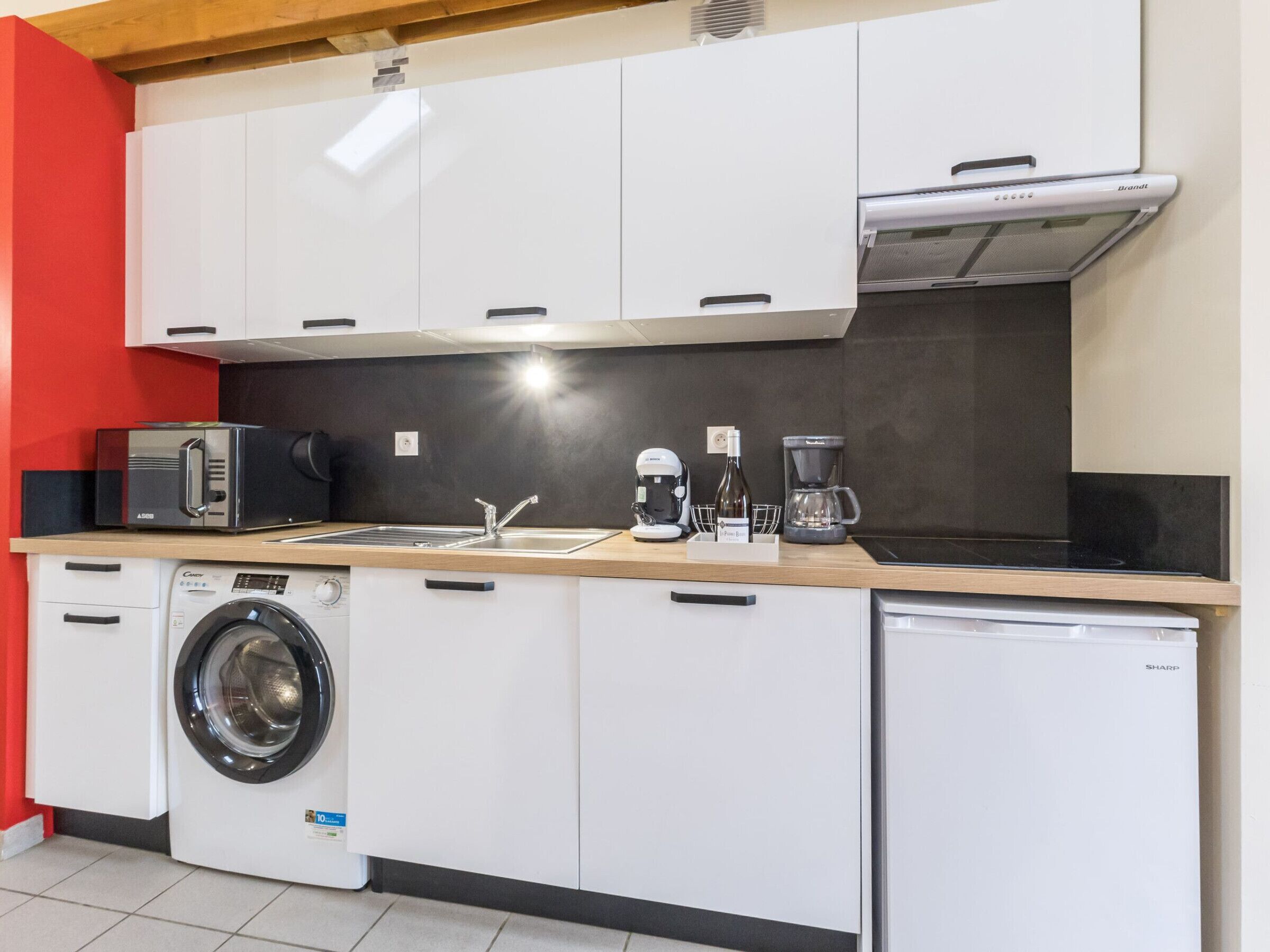 A compact kitchen with a washing machine, dishwasher, microwave, coffee maker, and a toaster.