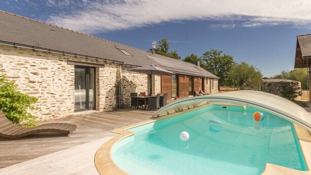 Ein Gebäude aus Stein mit Pool, Holzterrasse und Sitzbereich im Freien.